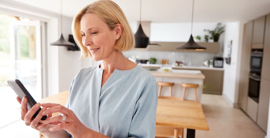 Woman holding a smartphone in a room filled with sunlight